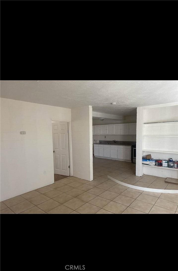 unfurnished living room with a textured ceiling and light tile patterned floors