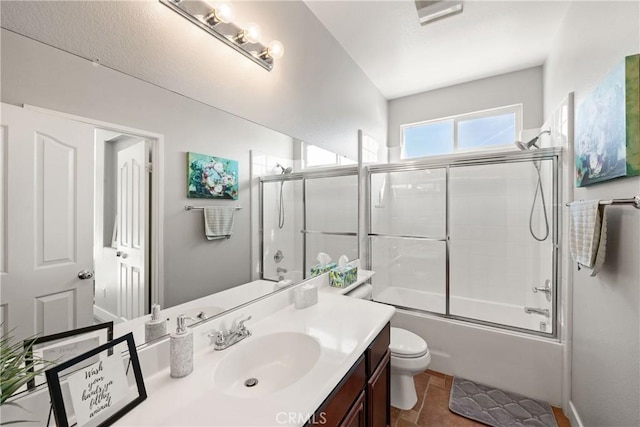 full bathroom featuring vanity, tile patterned floors, shower / bath combination with glass door, and toilet