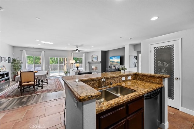 kitchen featuring sink, light tile patterned floors, dishwasher, ceiling fan, and a kitchen island with sink