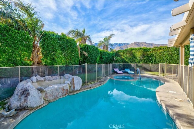 view of swimming pool with a mountain view and an in ground hot tub