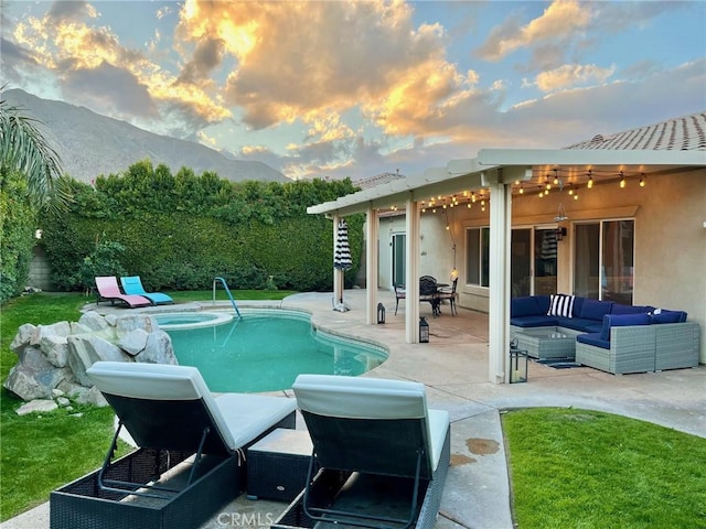 pool at dusk featuring an in ground hot tub, an outdoor living space, a mountain view, and a patio