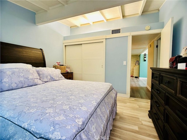 bedroom with light wood-type flooring and beamed ceiling