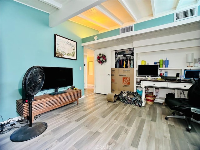 home office featuring light wood-type flooring and beamed ceiling