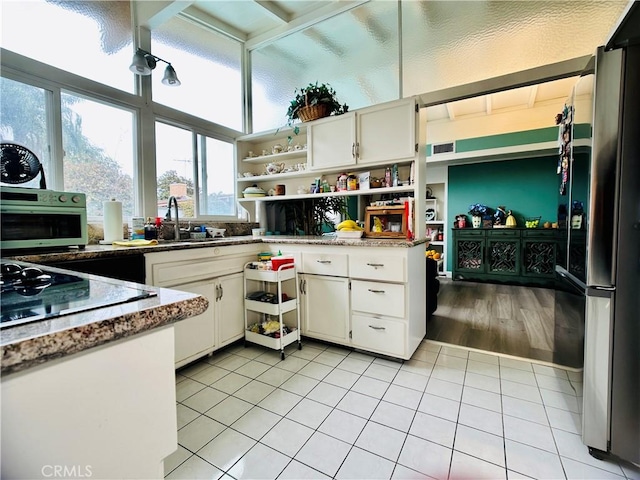 kitchen featuring light tile patterned floors, white cabinetry, stainless steel fridge, and sink