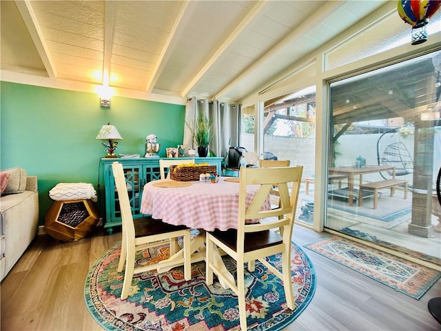 dining area featuring vaulted ceiling with beams and light hardwood / wood-style flooring