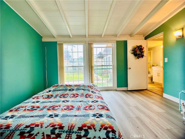 bedroom with vaulted ceiling with beams, ensuite bathroom, and hardwood / wood-style floors