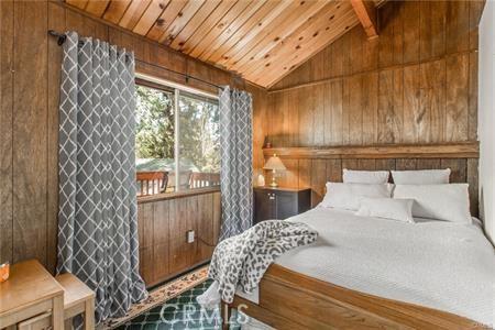 bedroom with lofted ceiling with beams and wood walls