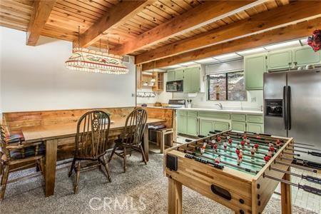 recreation room featuring beam ceiling, wooden ceiling, and dark carpet