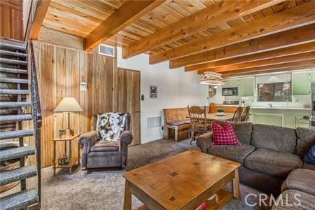 carpeted living room with beamed ceiling and wooden ceiling