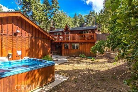 rear view of property featuring a wooden deck and a hot tub