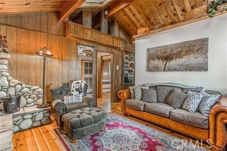 living room with beamed ceiling, hardwood / wood-style flooring, wooden ceiling, and wood walls