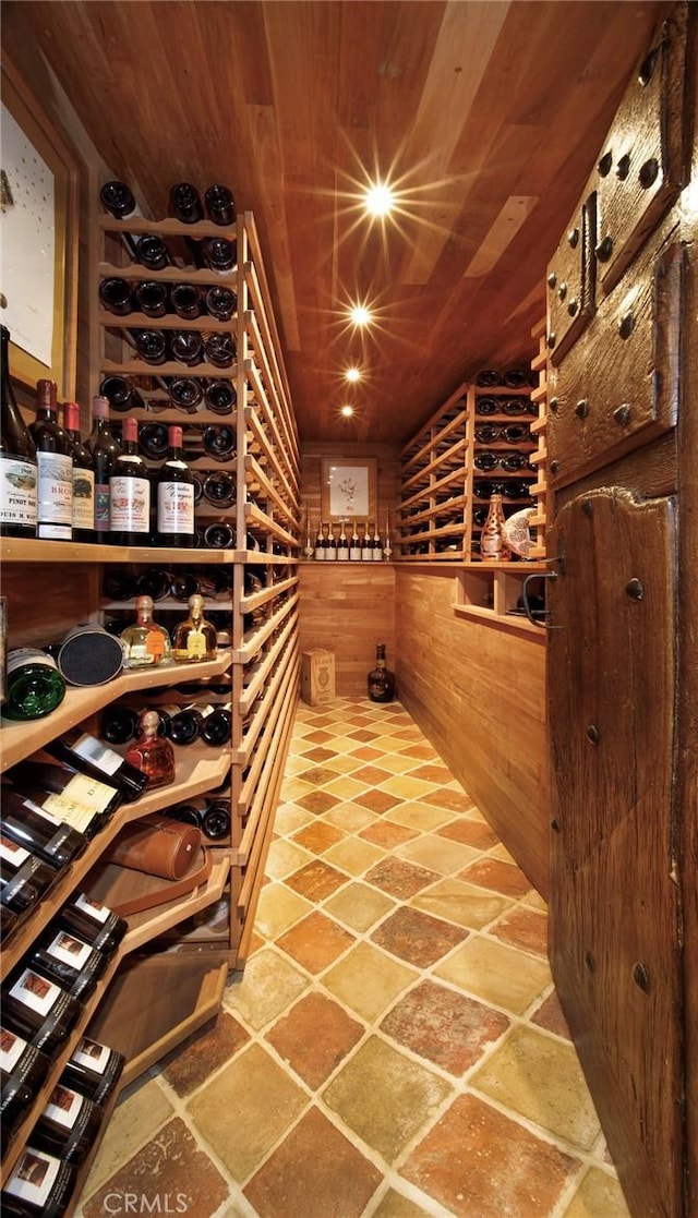 wine area featuring wood ceiling, wood walls, and stone finish flooring
