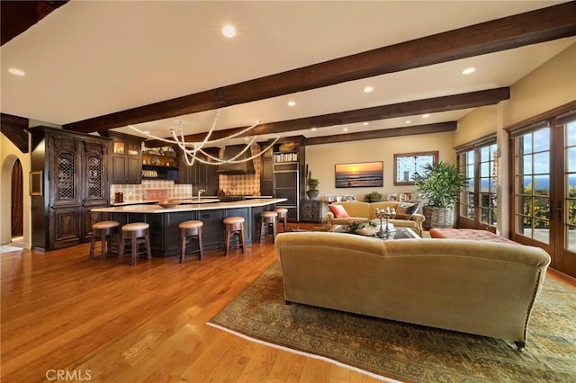 living area with arched walkways, beam ceiling, wood finished floors, and recessed lighting
