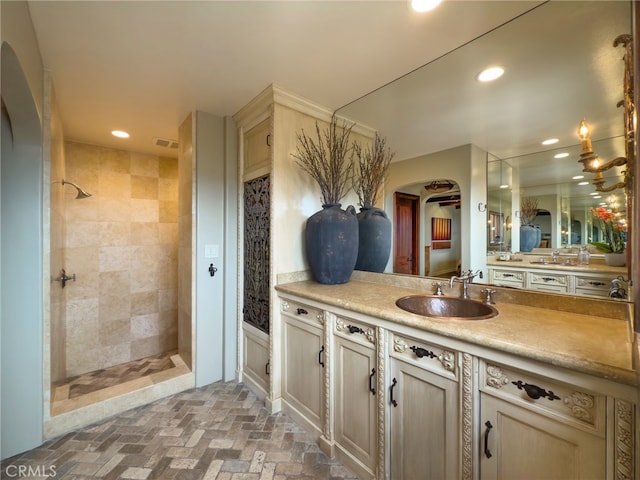 bathroom with a tile shower, vanity, visible vents, and recessed lighting