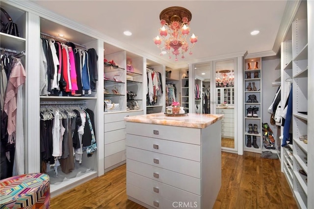 walk in closet with wood finished floors and a notable chandelier