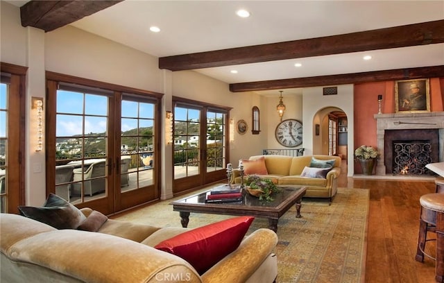 living area featuring wood finished floors, arched walkways, french doors, beam ceiling, and recessed lighting