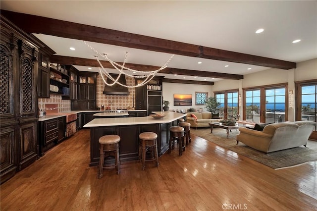 kitchen with hardwood / wood-style flooring, a kitchen breakfast bar, beamed ceiling, and light countertops