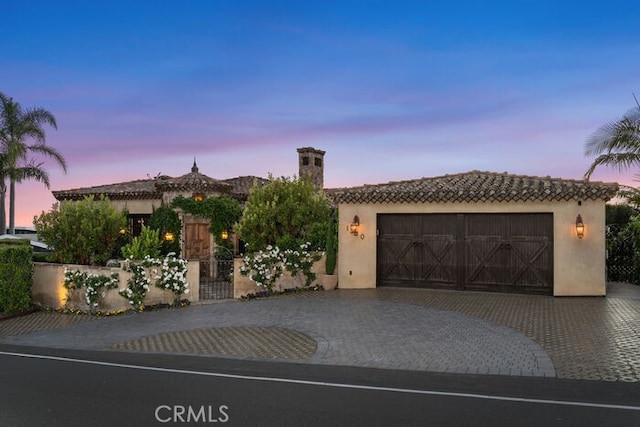 1330 Temple Hills Dr, Laguna Beach, CA 92651 - mediterranean / spanish house featuring stucco siding, decorative driveway, an attached garage, and a tiled roof