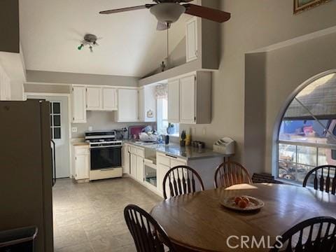 kitchen featuring white refrigerator, range, a healthy amount of sunlight, and white cabinetry