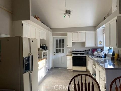 kitchen featuring white fridge with ice dispenser, white cabinets, stove, and sink