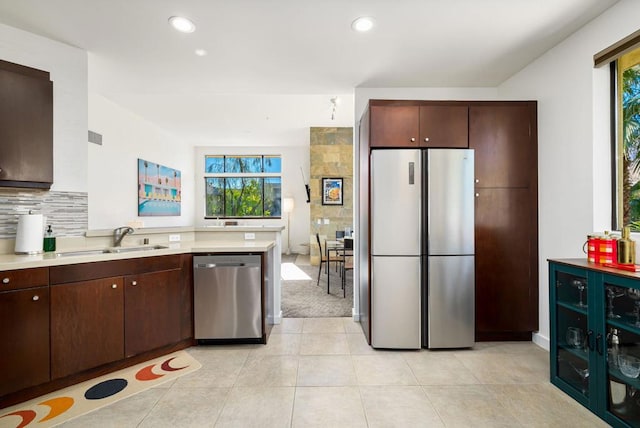 kitchen featuring dark brown cabinets, light tile patterned flooring, sink, and stainless steel appliances