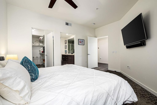 carpeted bedroom featuring ceiling fan, a walk in closet, connected bathroom, and a closet