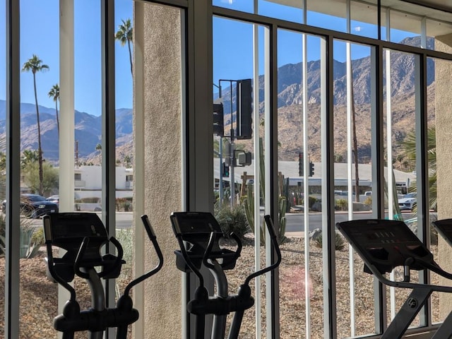 exercise room with a mountain view, expansive windows, and a healthy amount of sunlight