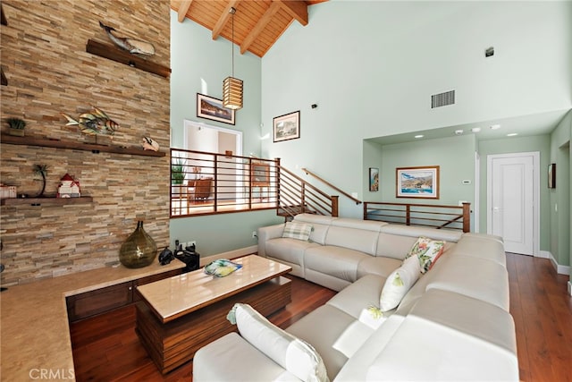 living area with visible vents, beamed ceiling, wood finished floors, baseboards, and wood ceiling