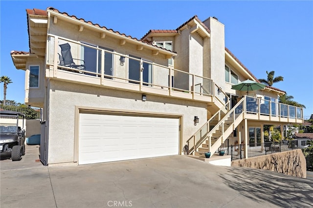 exterior space featuring concrete driveway, stairway, an attached garage, and stucco siding