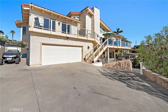 view of front facade with stucco siding, an attached garage, concrete driveway, and stairs