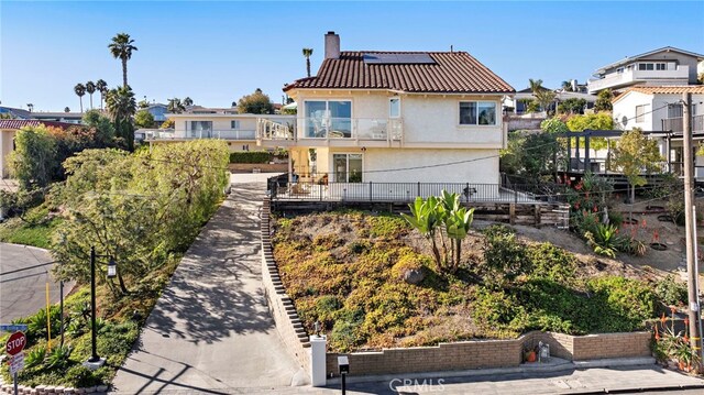 back of property featuring a balcony and solar panels