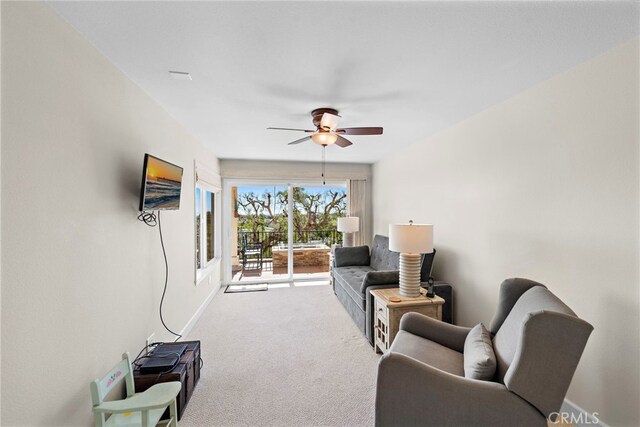 carpeted living room with baseboards and a ceiling fan