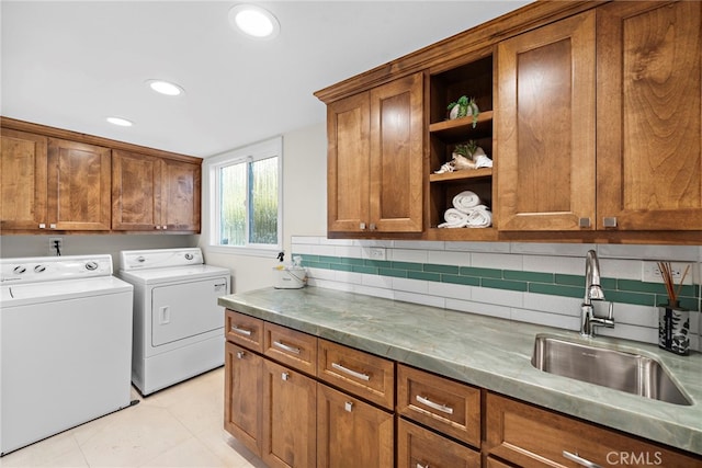 washroom with cabinets, washing machine and clothes dryer, sink, and light tile patterned floors