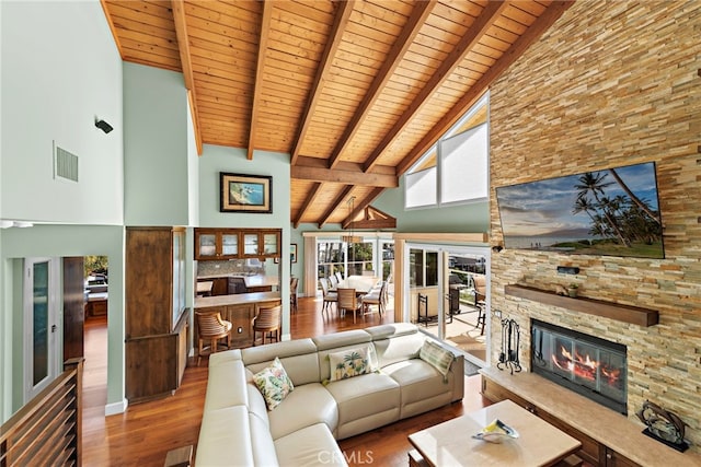 living area featuring visible vents, beam ceiling, a fireplace, wooden ceiling, and wood finished floors