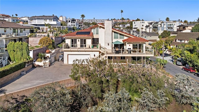 exterior space featuring stucco siding, a residential view, solar panels, and driveway