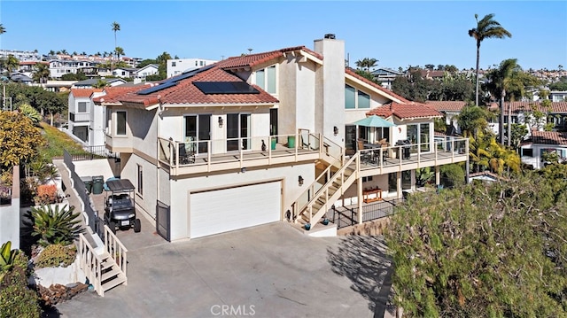 back of house featuring a balcony, a garage, and solar panels