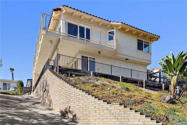 rear view of house with stucco siding and a tile roof