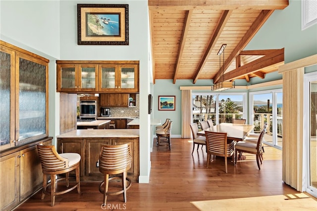 kitchen with tasteful backsplash, a kitchen breakfast bar, stainless steel oven, kitchen peninsula, and beam ceiling