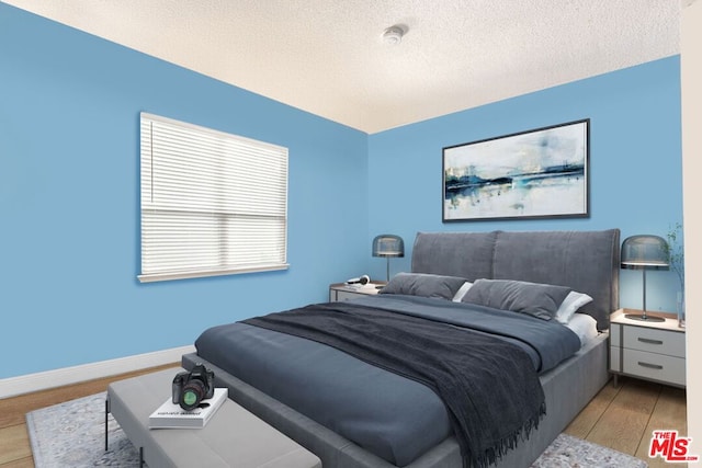 bedroom featuring light hardwood / wood-style flooring and a textured ceiling