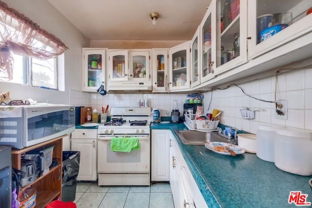 kitchen with sink, light tile patterned floors, tasteful backsplash, white appliances, and white cabinets