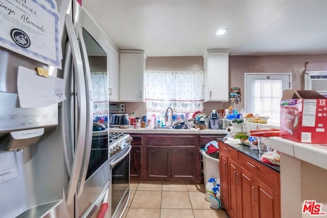 kitchen featuring appliances with stainless steel finishes, white cabinetry, tile counters, and light tile patterned flooring