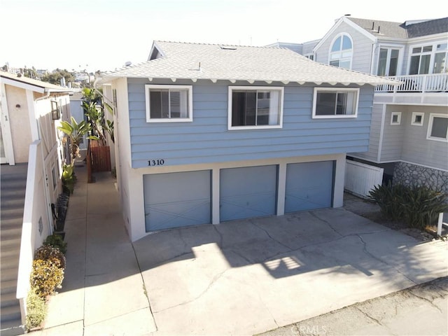 view of front facade featuring a garage, concrete driveway, and roof with shingles