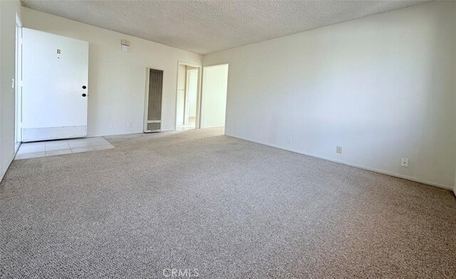 unfurnished room featuring a textured ceiling and light colored carpet