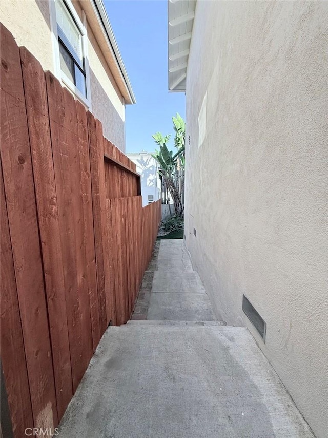 view of side of home with fence and stucco siding