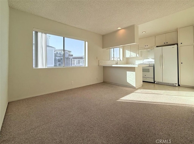 kitchen with range, open floor plan, freestanding refrigerator, a peninsula, and light countertops