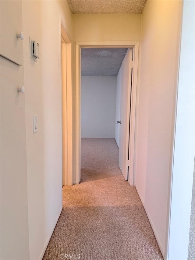 hallway featuring a textured ceiling and carpet flooring