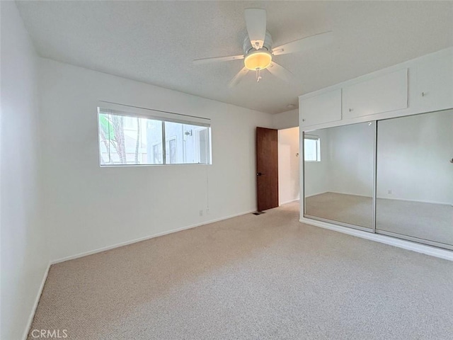 unfurnished bedroom with multiple windows, light colored carpet, a closet, and ceiling fan