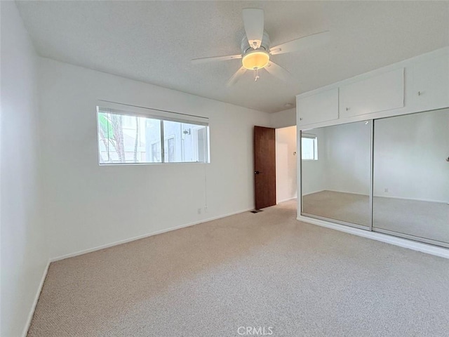 unfurnished bedroom featuring light carpet, a closet, a ceiling fan, and baseboards