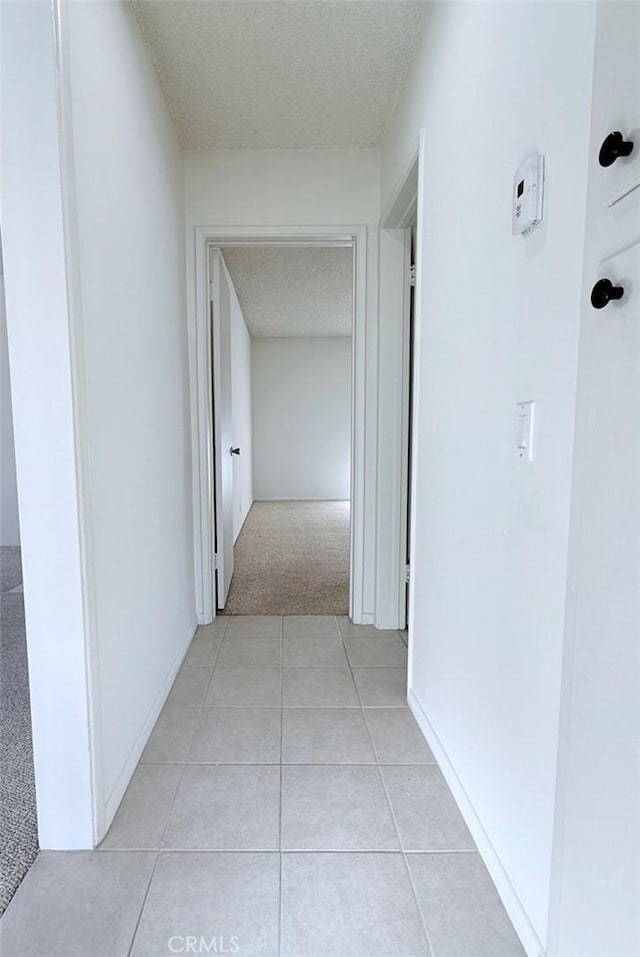 corridor with light colored carpet and a textured ceiling