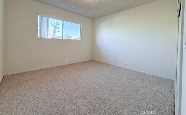 empty room featuring a textured ceiling, carpet flooring, and baseboards